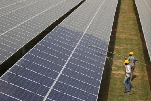 Workers clean photovoltaic panels inside a solar power plant in Gujarat, July 2, 2015. REUTERS/Amit Dave/Files